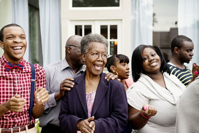 Happy family and friends standing against house