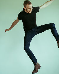 Full length of young man jumping over white background