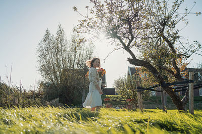 Woman standing by tree on field