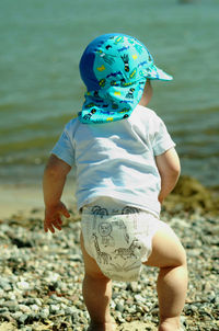 Baby in cap walking on shore at beach