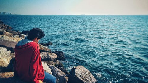 Rear view of man looking at sea against sky