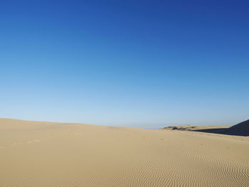 Scenic view of desert against clear blue sky