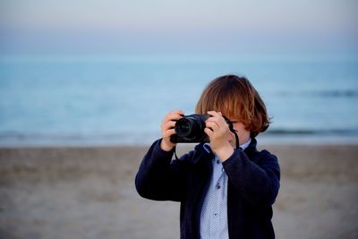Boy photographing from camera at beach