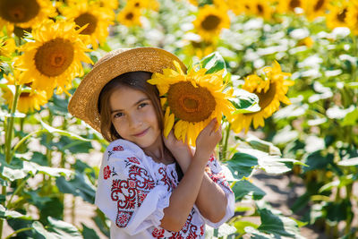 Portrait of smiling girl with sunflower at field