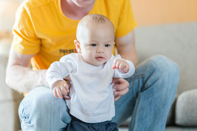 Midsection of father and son sitting on floor at home