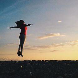 Full length of young woman jumping against clear sky