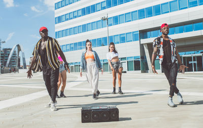 Friends dancing against building in city