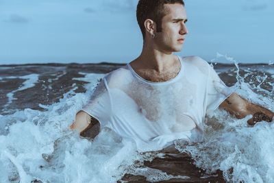 Young man swimming in splashing sea