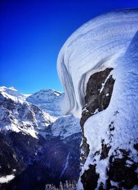 Scenic view of snow covered mountains against clear blue sky