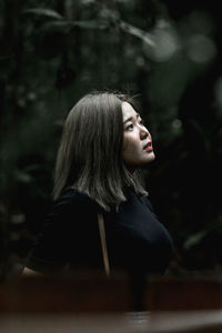 Portrait of young woman looking away in forest