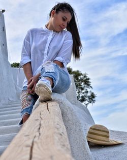 Low angle view of woman sitting against sky