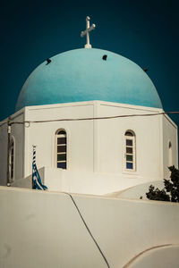 Low angle view of cross on building against blue sky