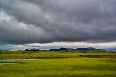 Scenic view of green landscape against cloudy sky