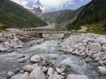 Scenic view of rocky mountains with a bridge over the creek