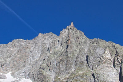 Low angle view of rocky mountains against clear blue sky