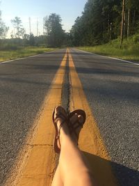 Low section of person on road against trees