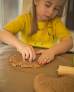 Girl cutting dough in kitchen