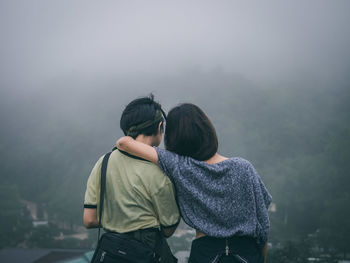 Rear view of couple walking on snow covered landscape during rainy season