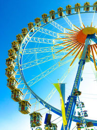 Low angle view of ferris wheel against clear blue sky