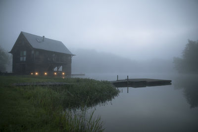 Log cabin at lakeshore during foggy weather