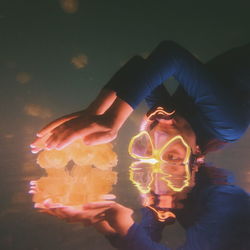 Woman wearing illuminated scuba mask holding jelly fish while snorkeling in sea