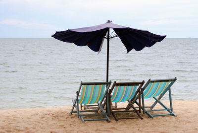 Deck chairs and umbrella at beach on sunny day