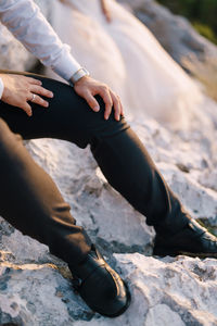 Low section of woman sitting on rock