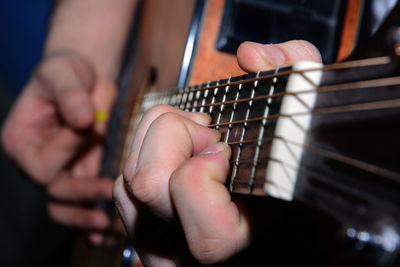 Midsection of man playing guitar indoors