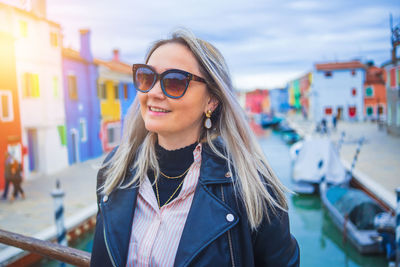 Portrait of young woman wearing sunglasses standing in city