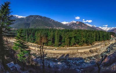 Scenic view of trees and mountains against blue sky