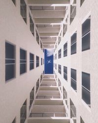 Directly below shot of building with airplane flying against sky