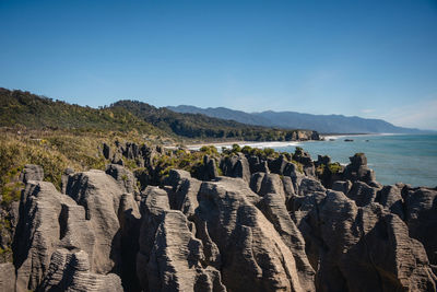 Panoramic view of rocky mountains against clear blue sky