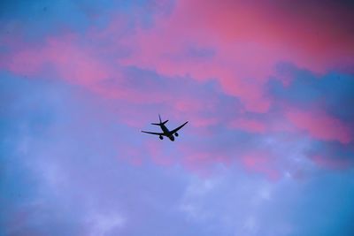 Low angle view of silhouette airplane against sky during sunset