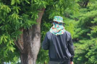 Rear view of woman standing against trees