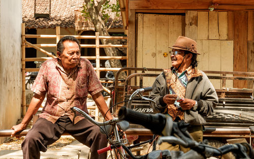 This photo shows two old men talking to each other at a used bicycle market.