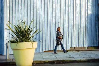 Woman sitting on potted plant in city