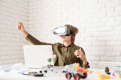 Nice teen boy in vr glasses sitting at the table playing game