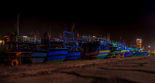 Boats moored at harbor against sky at night