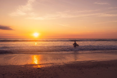 Silhouette person on beach against sky during sunset