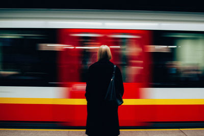 Rear view of woman standing at railroad station platform