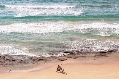 Aerial view of man bicycling on beach