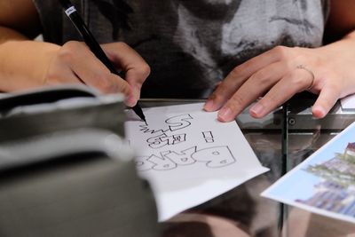Midsection of woman holding paper with text on table
