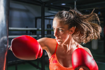 Woman wearing boxing gloves while practicing in gym