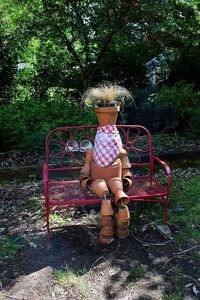 Rear view of girl sitting on seat against trees