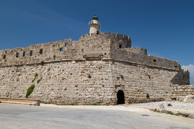 Kastell agios nikolaos with lighthouse at mandraki harbour in rhodes city on greek island rhodes