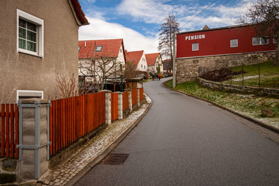 Empty road amidst buildings against sky