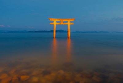 Torii gate in sea against blue sky