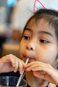 Close-up portrait of cute girl drinking