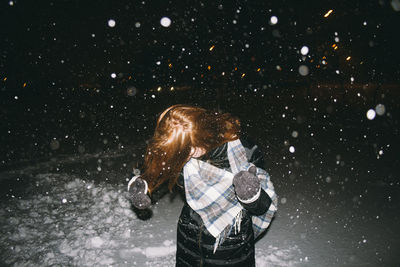 Woman standing on field during snowfall at night