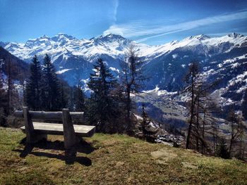 Empty wooden bench on mountain against sky
